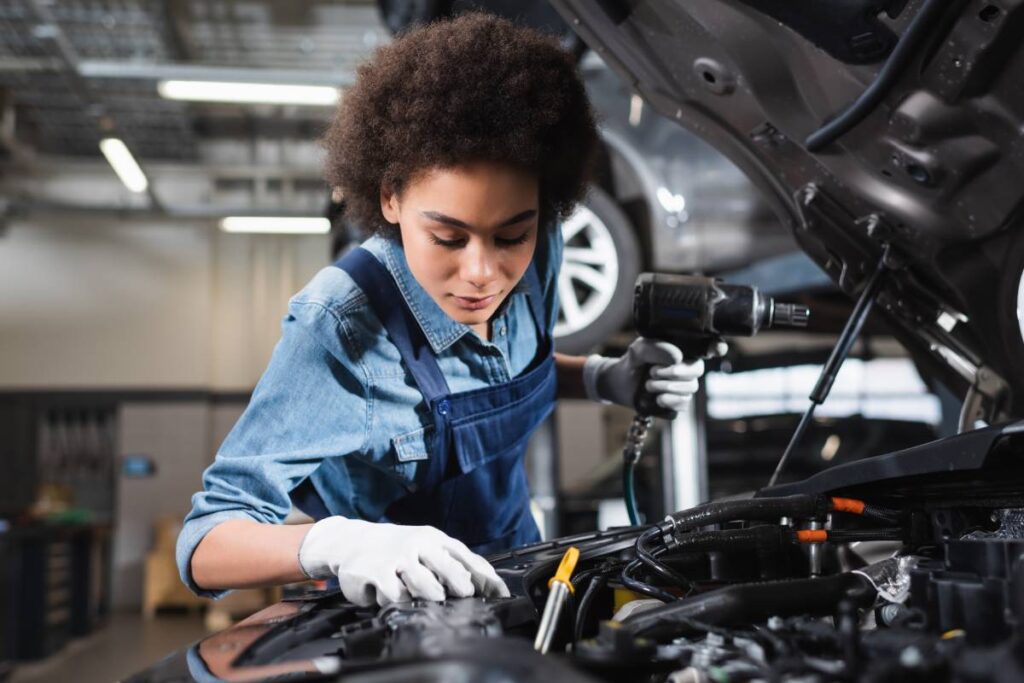 A certified mechanic working under the hood of a vehicle at a transmission shop