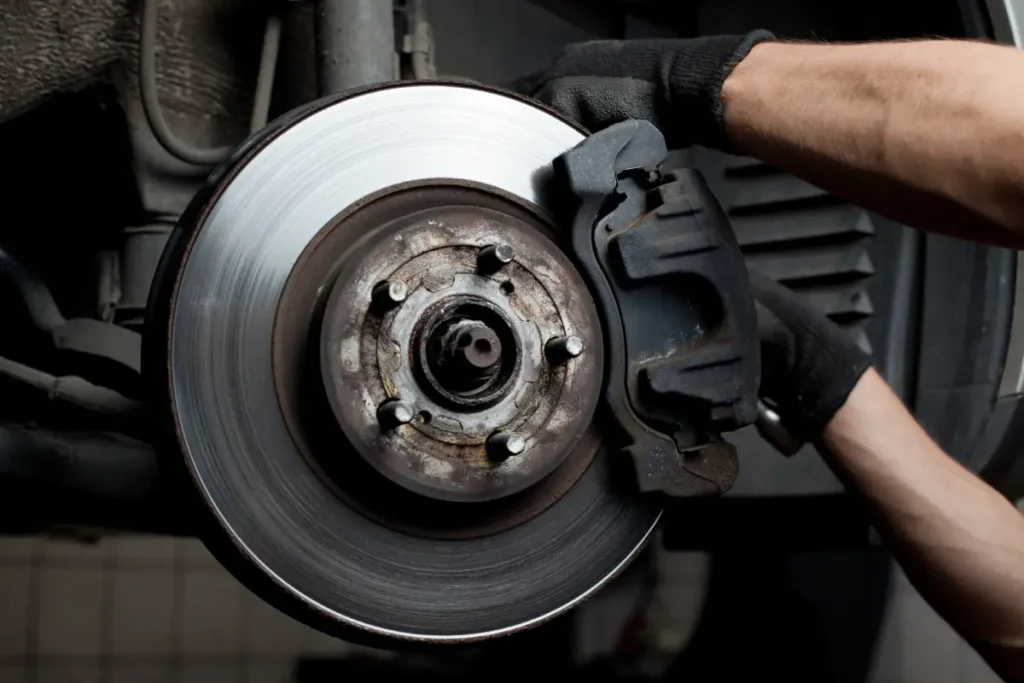 A car technician working on a vehicle's brakes and brake pads in an auto shop